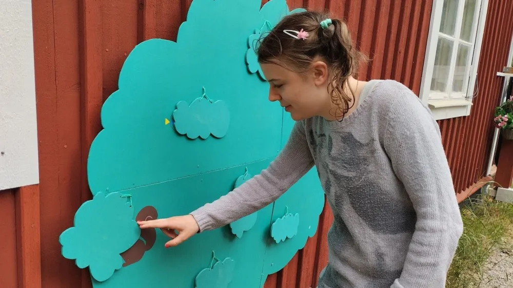 Girl with autism discovering what is hiding in the tree at Axmar Yara sensory and play garden