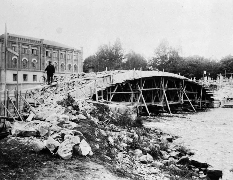 Drottningbron under byggnation, samt Gefle Valsqvarn till vänster. Fotat från andra sidan ån.