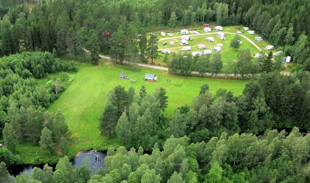 Vybild över husvagnscamping, grön äng och skogar