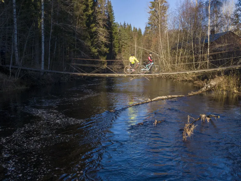 Två cyklister står på en bra och tittar  över älven