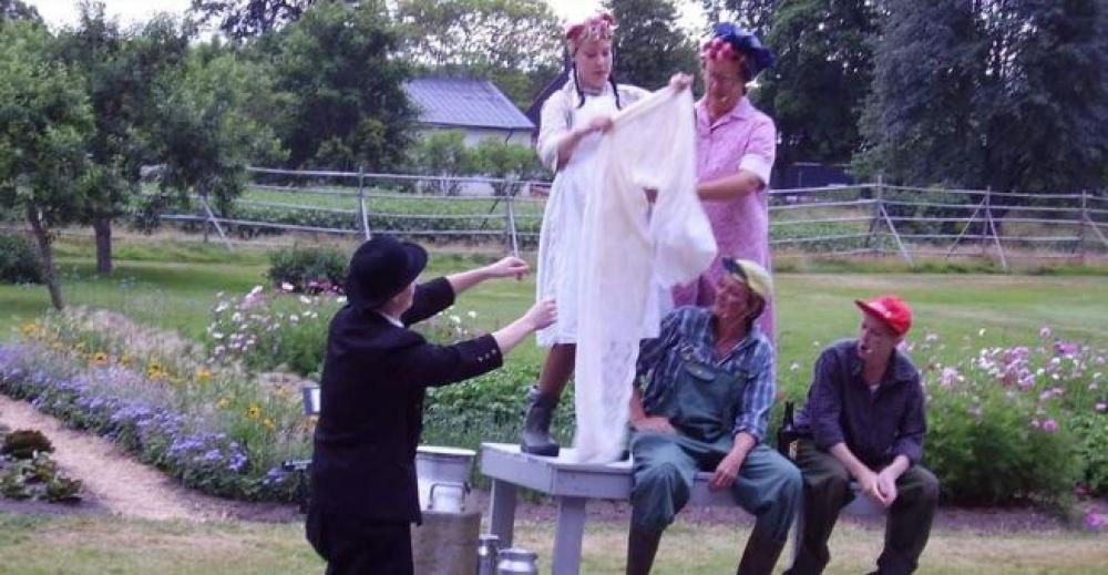 Bild från teaterföreställning, 5 människor vid en mjölkpall.